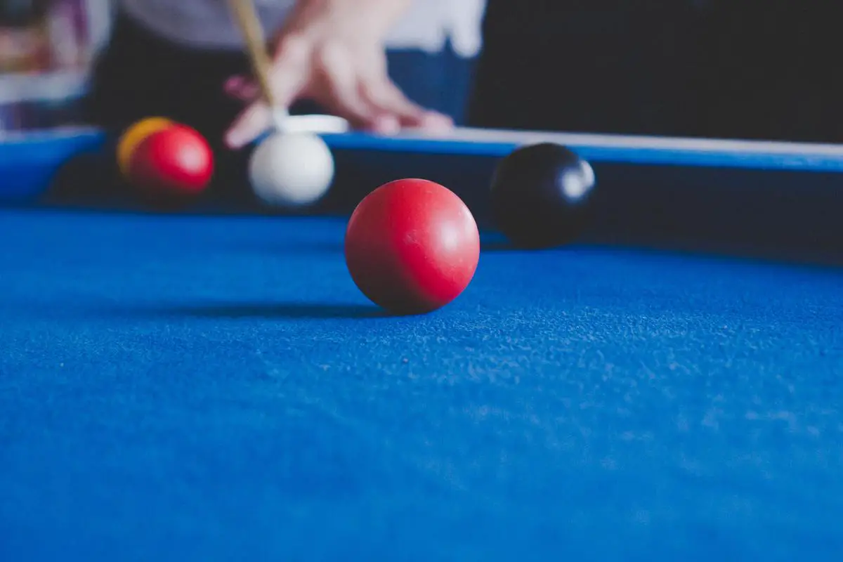 A billiards player executing a difficult trick shot, demonstrating skill and precision.